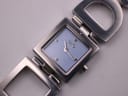 Close-up front view of the D&G Time watch dial, featuring a light blue face, polished baton indices, and the D&G logo below 12 o'clock.