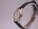 Right side view of the Tissot PR 50 watch on a display stand, highlighting the gold-tone crown and bezel.