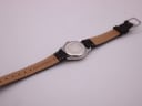 Rear view of the Tissot PR 50 watch laid flat, displaying the stainless steel case back and the 'Genuine Leather' stamp on the strap's interior.