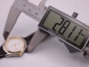 A digital caliper measuring the case diameter of the Tissot PR 50 watch, displaying a precise reading of 28.11mm.