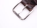 Close-up of the stainless steel pin buckle of the brown leather strap, clearly showing the 'TISSOT' engraving.