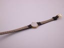 View of the watch case back and the underside of the brown leather strap, showing 'GENUINE LEATHER 10'.
