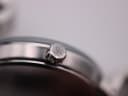 Extreme close-up of the textured, signed 'MK' crown on the side of the watch case.