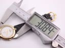 Digital caliper measuring the case diameter of the watch, displaying 30.84mm on its screen.
