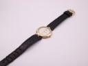 Top-down view of Raymond Weil 5350 watch with gold case and full black leather strap on a white background.