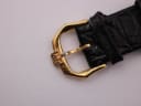 Close-up of the gold-tone buckle with 'RW' logo engraving on the black leather strap.