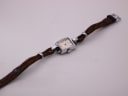 Overhead angled shot of the full Helvetia watch, displaying the rectangular case and the length of the brown woven fabric strap with its buckle.