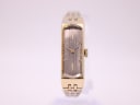 Front view of gold tone Seiko rectangular watch with silver textured dial and gold baton indices.