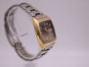Another angled view of the Seiko watch on a clear stand, highlighting the gold-plated case from a different perspective.