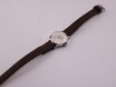 Overhead view of the Seiko watch and brown leather strap extended on a white surface.