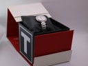 Tissot watch displayed inside its original red and white branded presentation box with a black cushion.