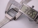 Digital caliper measuring the case width of the Seiko A159-5009-G watch, showing an exact measurement of 34.95mm on the display.