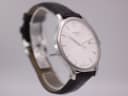 Angled view of the Tissot T063610 A watch, showcasing the clean white dial, slim profile, and brown leather strap.