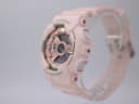 Right-side profile view of the pink G-SHOCK watch showing buttons and case texture on a clear stand.
