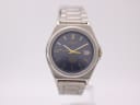 Front view of the Seiko V145-0AA0 solar titanium watch with a blue dial, gold baton indices, and date window.
