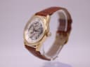 Angled side view of the PWC London watch from the right, highlighting the gold-tone case, crown, and brown leather strap