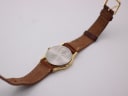 View of the watch case back and brown leather strap.