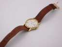 Overhead view of the Timex watch on its brown leather strap, laid out straight.
