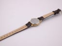 Back view of the watch and the underside of the brown leather strap, showing 'genuine leather' marking.