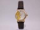 Front view of the gold-tone Warner Bros. Tweety Bird watch with a white dial and brown leather strap on a watch stand.