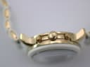 Close-up of the watch's right side, focusing on the gold-tone crown with the "MK" logo and the two chronograph pushers.