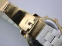 Close-up of the gold-tone fold-over clasp on the white ceramic bracelet, engraved with "MICHAEL KORS".