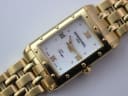Close-up front view of the Raymond Weil Tango dial, showing Roman numerals, gold hands, and mother-of-pearl texture.