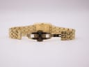 View of the watch's gold-tone steel bracelet with its deployant clasp open, showing the internal mechanism.