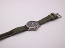 Full length view of Lorus watch with green fabric strap laid out.