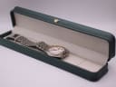 Seiko SQ 100 watch resting in a generic green leatherette presentation box.