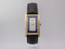 Front view of the Gucci 2600 M watch, showing its gold rectangular case, blue and white dial, and black leather strap.