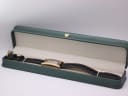 Gucci watch displayed open in a generic green leatherette presentation box, a studio prop.