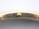 Extreme close-up of the gold-tone crown of the Gucci 2600 M, featuring the embossed Gucci logo.