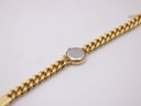 View of the watch from the rear, showing the plain polished case back and the extended gold-tone bracelet.