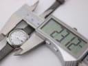A digital caliper measuring the case diameter of the Seiko watch, with the display showing a precise reading of 27.12mm.