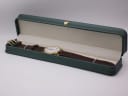 Tissot watch presented open in a generic dark green leatherette display box with a small gold crown emblem.