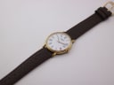 Overhead view of the Tissot watch with its brown leather strap extended on a white background.