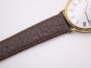 Close-up of the textured brown leather strap with stitching near the watch lugs, showing its grain.