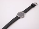 Top-down view of the Michel Jordi watch with its black leather strap laid flat.