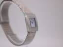 Angled side view of the Tissot L610K case and mesh bracelet on a display stand.
