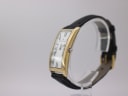Angled side view of the Maurice Lacroix watch, showing the curved gold-plated case and crown, with the black leather strap.