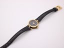 Top-down view of the Gucci 2000L watch with its black leather strap laid out flat, displaying the gold-toned buckle.