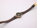 Back view of the Gucci 2000L watch case and strap, featuring the gold-toned interlocking G logo on the case back and wear on the strap's underside.