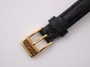 Close-up of the gold-toned pin buckle with 'GUCCI' engraving on the black leather strap.