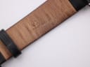 Close-up of the brown underside of the black leather strap, showing "Genuine Leather" inscription.