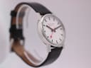 Another angled side view of the Mondaine watch on a clear display stand, highlighting the case profile.