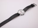 Top-down view of the Mondaine watch laid flat, displaying the full black leather strap and dial.