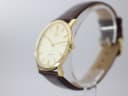 Angled side view of Roamer Slim Line watch, showing the slim gold-tone case and crown, with brown leather strap.
