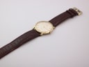 Overhead view of the Roamer Slim Line watch and its long brown leather strap, laid flat on a white surface.