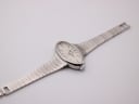 Top-down angled view of the Mortima watch, showcasing its oval case and the pattern of the integrated silver-tone steel bracelet laid flat.